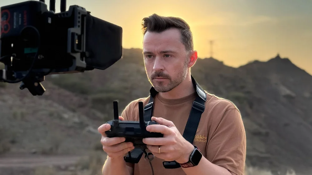 Drone pilot holding a remote controller in the mountains at sunset