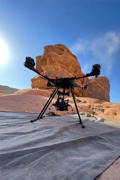 Heavy-lift cinema drone in front of a sandstone rock formation on a Hollywood film set in AlUla
