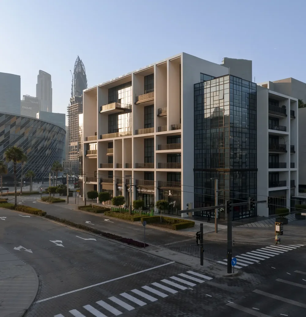 Low-altitude aerial photo of a modern residential building beside a curved road in Dubai