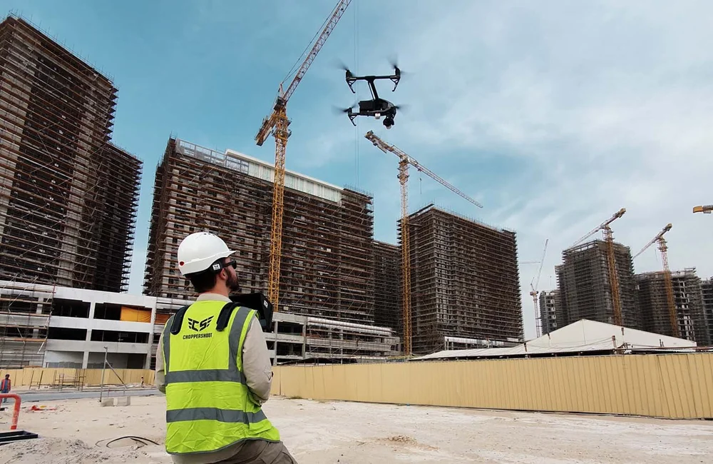 Drone pilot in a hard hat and hi-vis vest filming construction progress at the Expo 2020 site with an Inspire drone