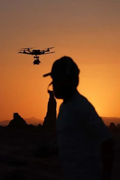 Drone pilot silhouetted at sunset with a heavy-lift Alta X drone in flight in Tabuk