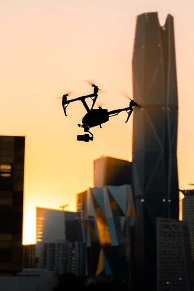 Camera drone silhouetted against a KAFD tower at sunset in Riyadh