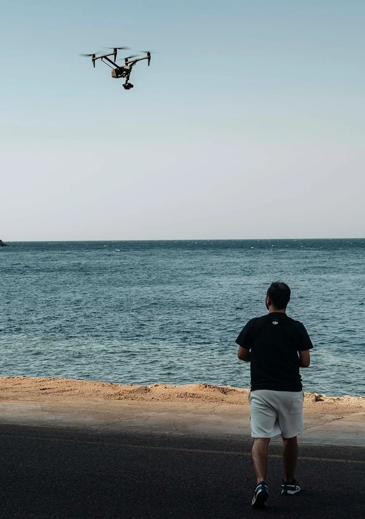 Pilot flying a drone over the sea from the shoreline