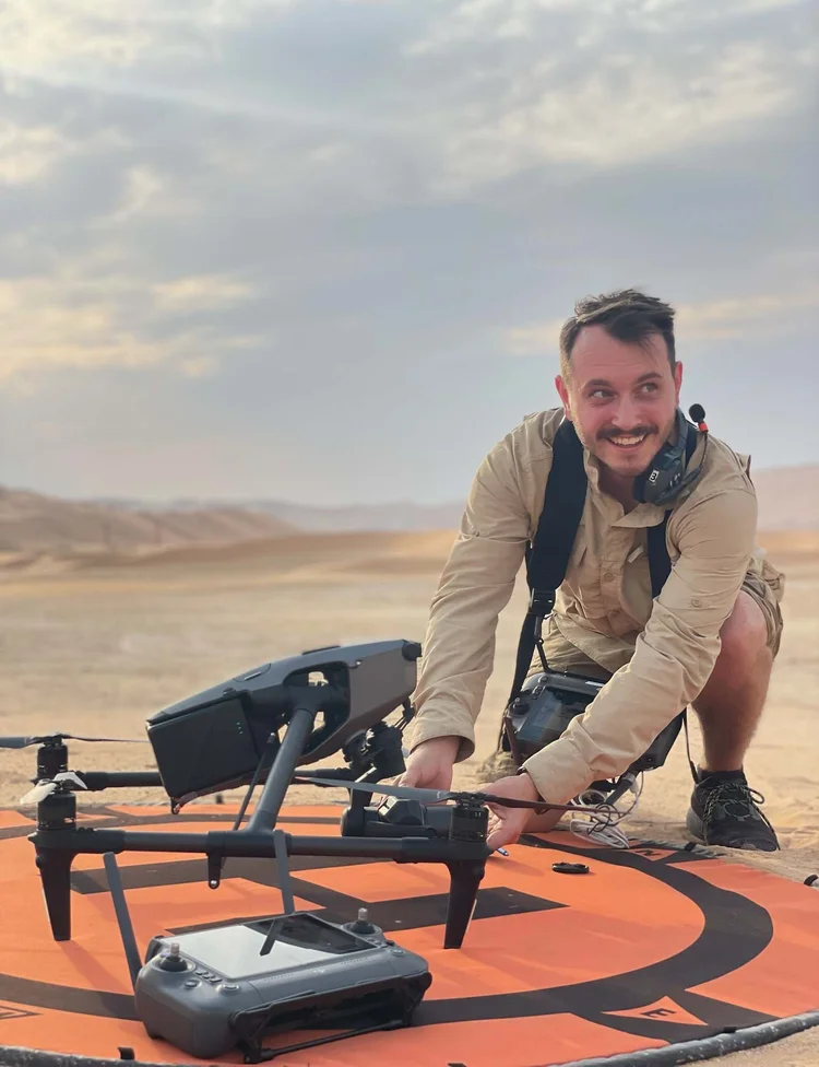 Pilot preparing an Inspire 3 and its controller on a landing pad in the desert