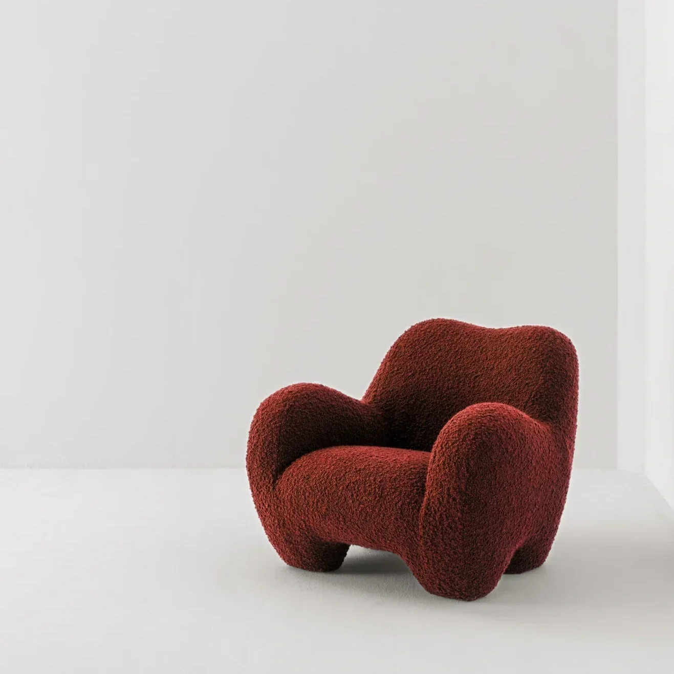 A red, textured, modern armchair in a minimalist white room