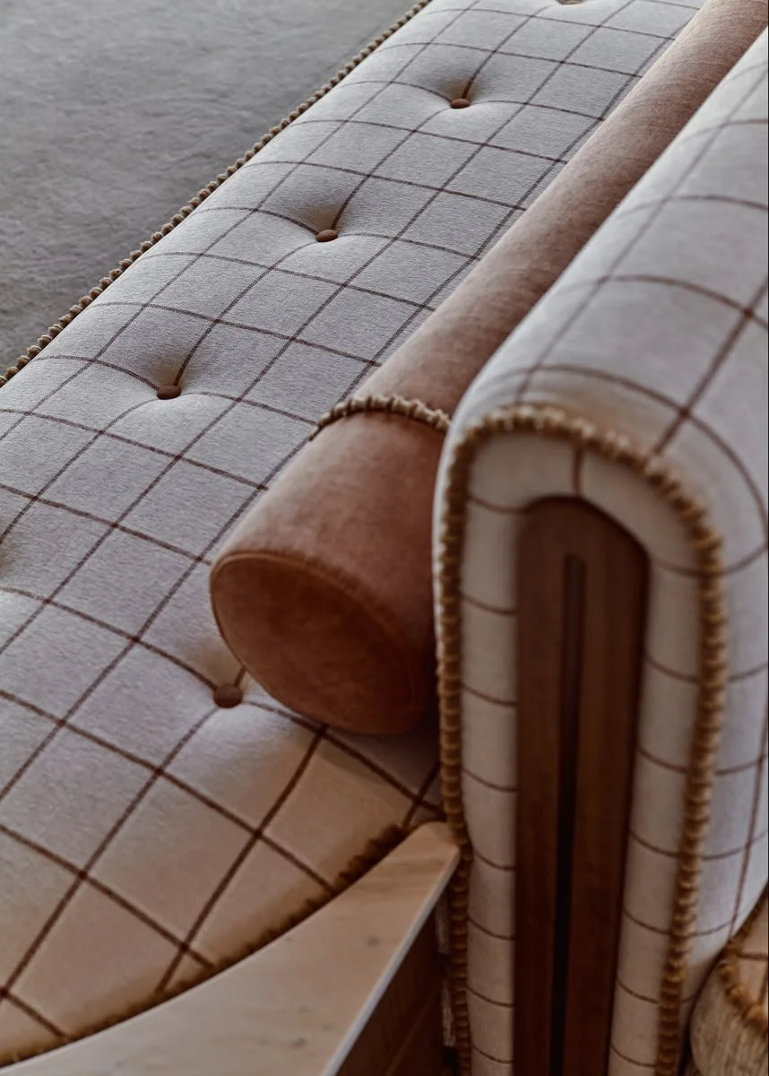 Close-up of banquette seating with pink plaid upholstery, wood accents, and button details.