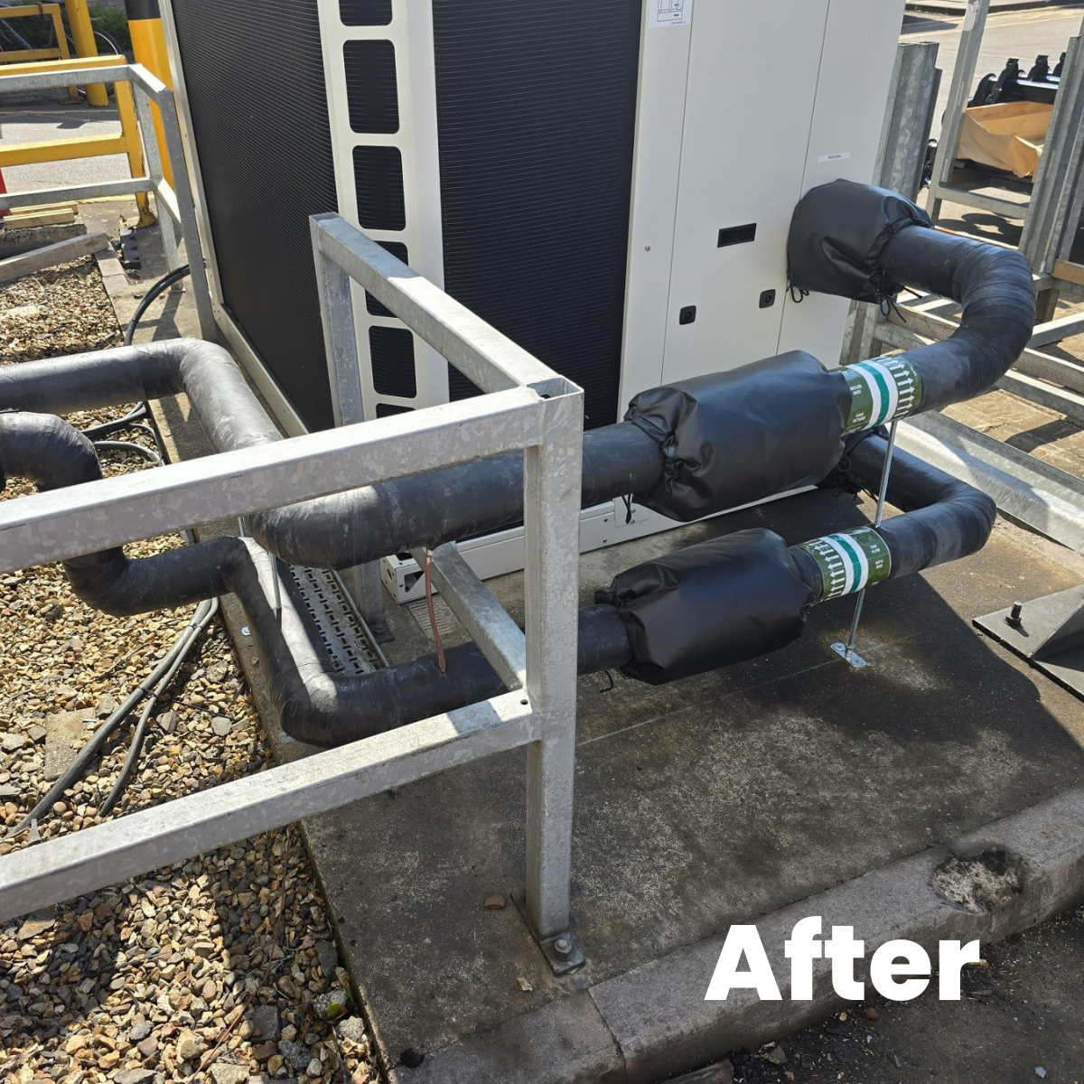 Installed HVAC system with insulated pipes and associated equipment outside, surrounded by a metal railing.
