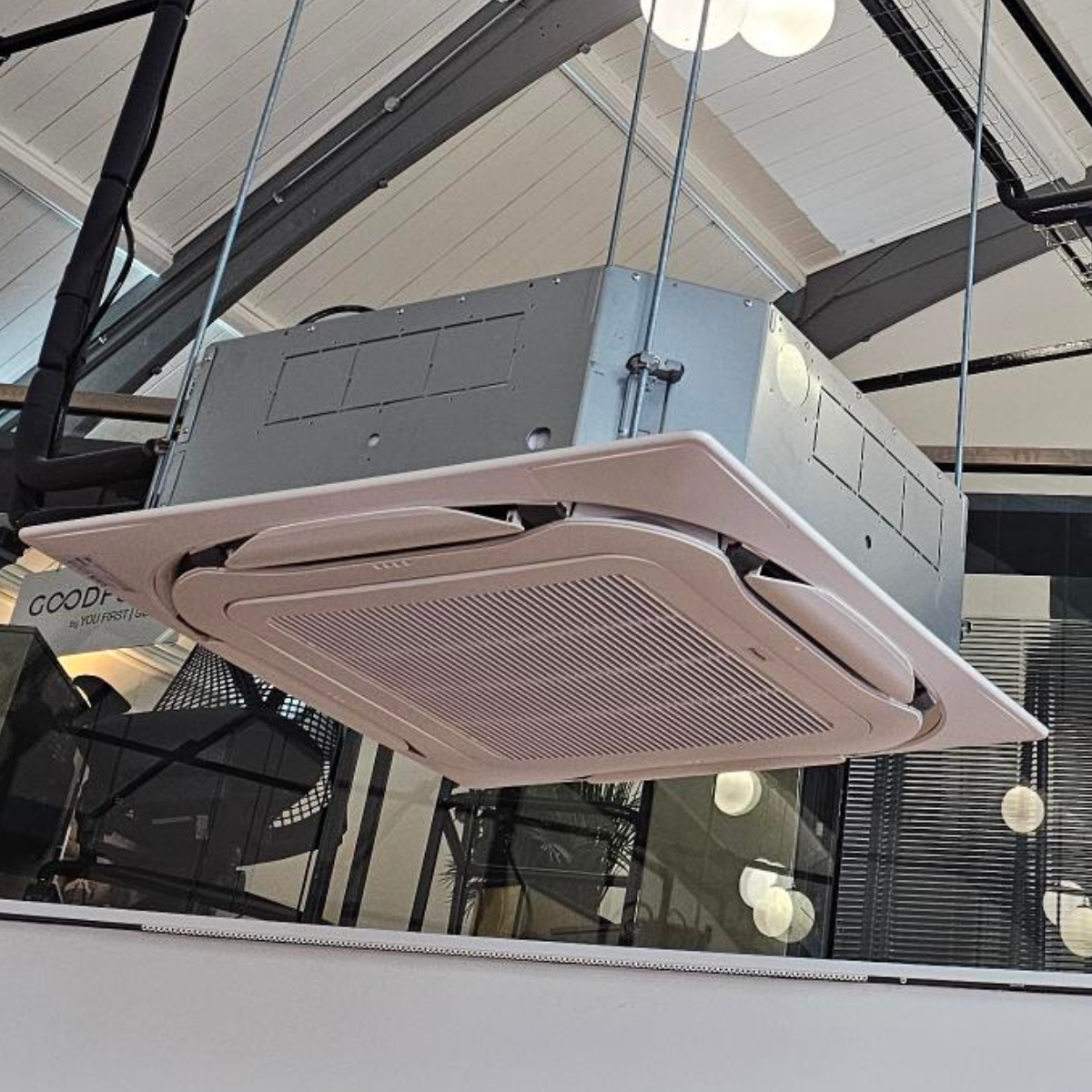 Ceiling-mounted air conditioning unit with a white vent grille in an indoor space.