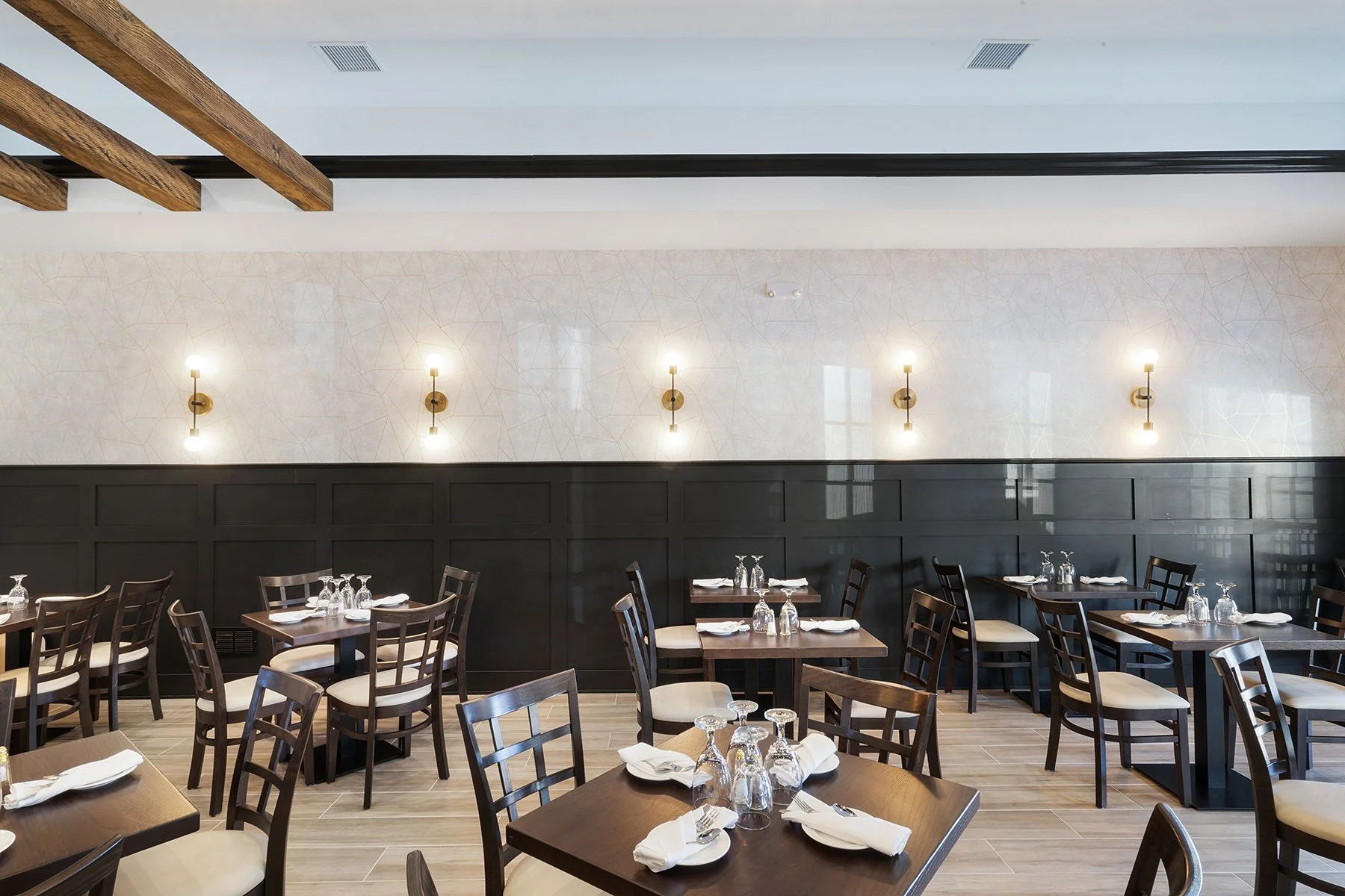 The room had a very long wall with no windows, so cozy seating vignettes were created with  board & battan wainscoting, commercially-rated Kravat wallpaper, and custom banquette fabrics. 