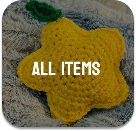 Yellow star-shaped crocheted toy with green leaf on top, placed on a textured gray fabric background.