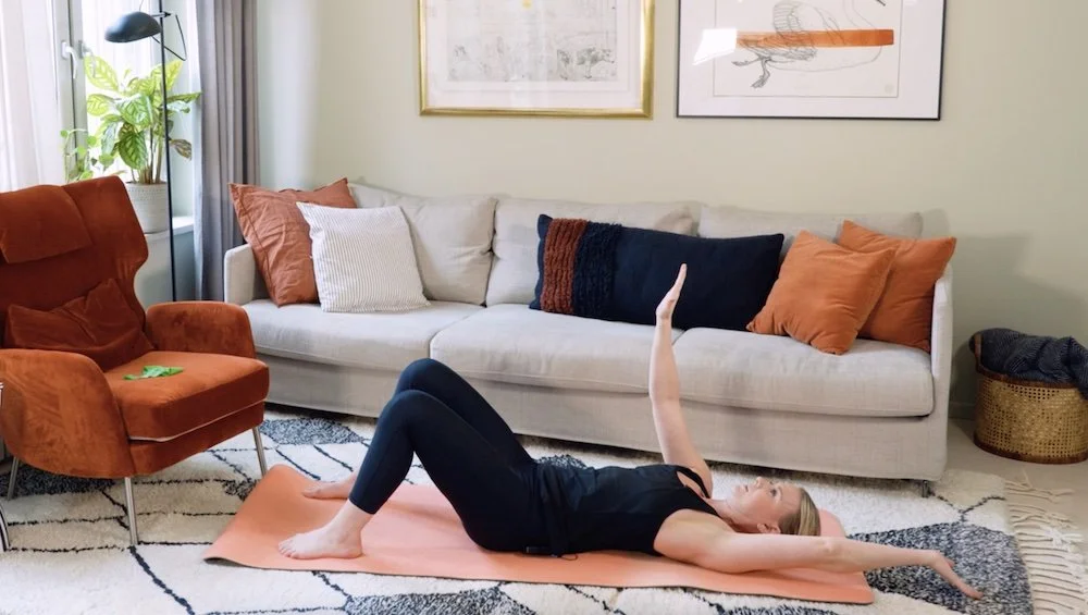 Kvinna som tränar efter förlossning. Övning dead bug arm.