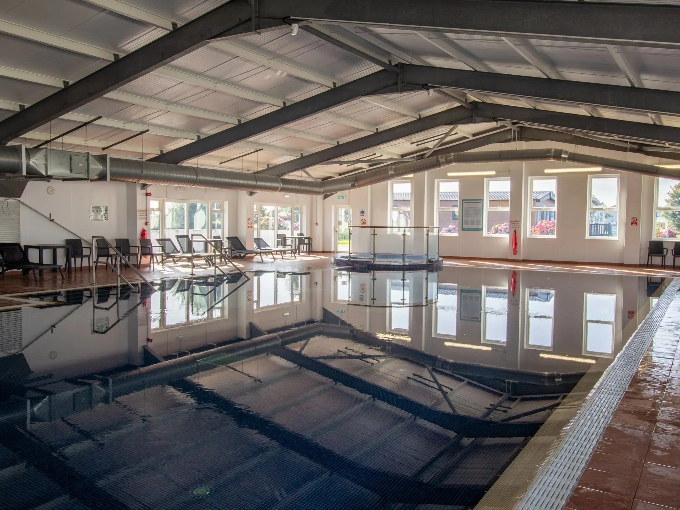 Heated indoor pool with splash pool and loungers at Newperran resort