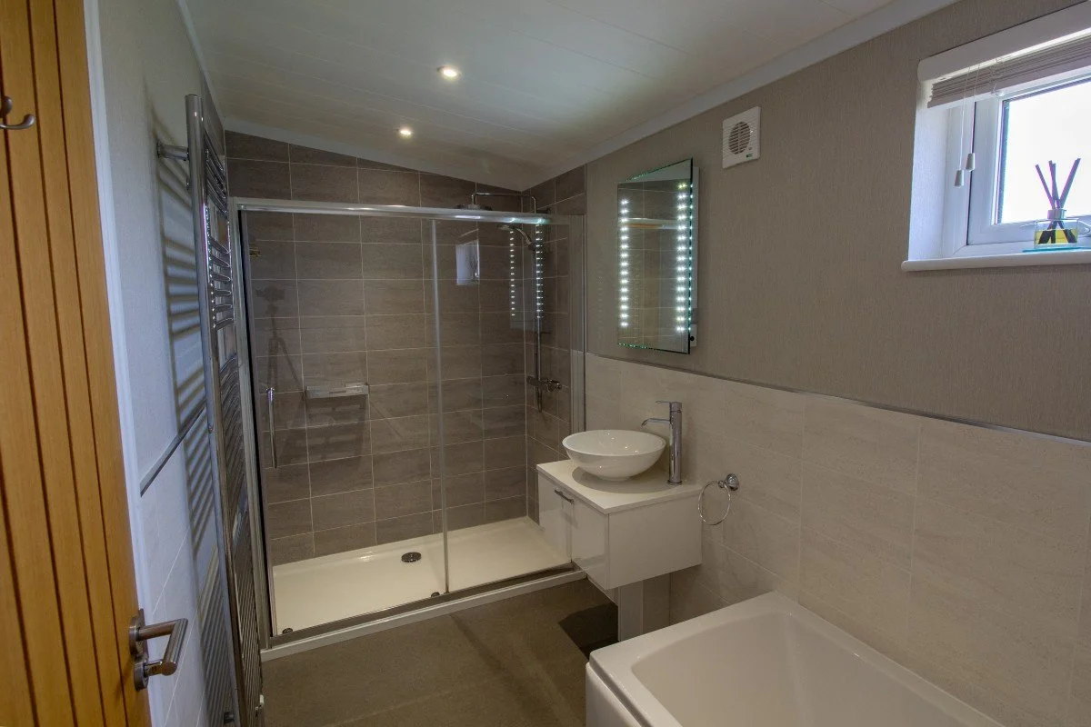 Spacious king-size en-suite bathroom at Teal Lodge Cornwall, featuring a double shower, bath, basin and heated towel rail.