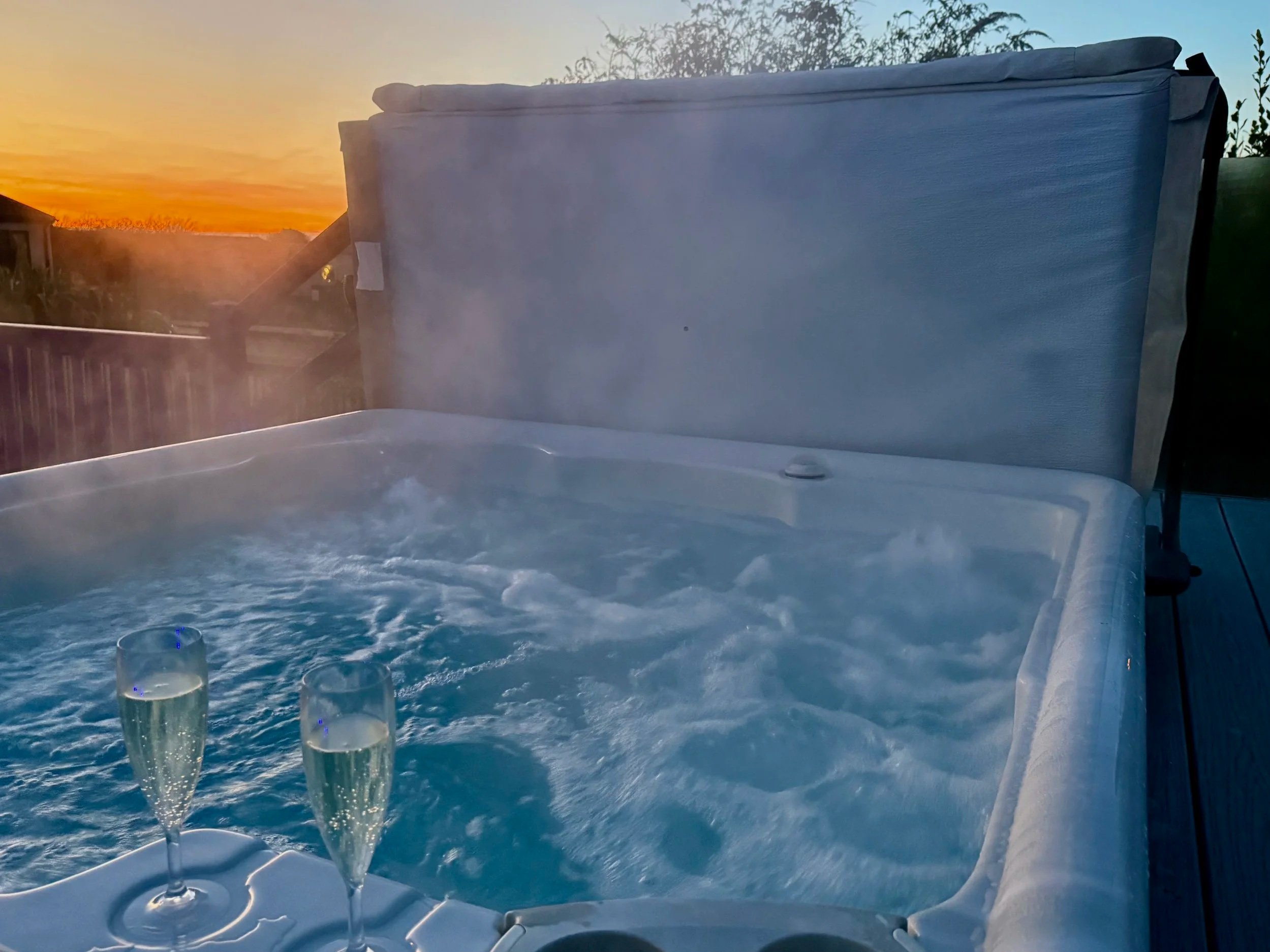 2 GLASSES OF CHAMPAGNE ON THE EDGE OF A BUBBLING & STEAMING HOT TUB AT SUNSET