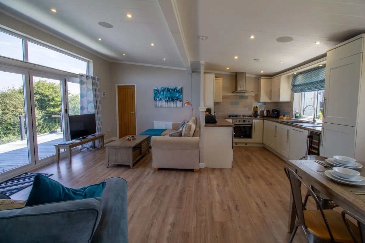Spacious open-plan living, dining and kitchen area at Teal Lodge Cornwall, with doors opening onto the rear decking.