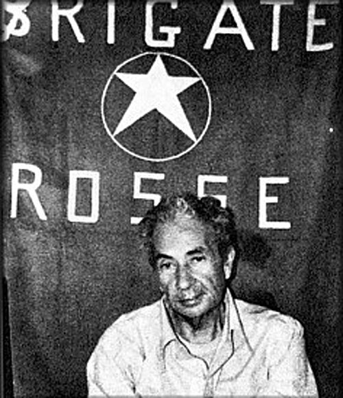 photo of a man in a white shirt posed in front of a sign