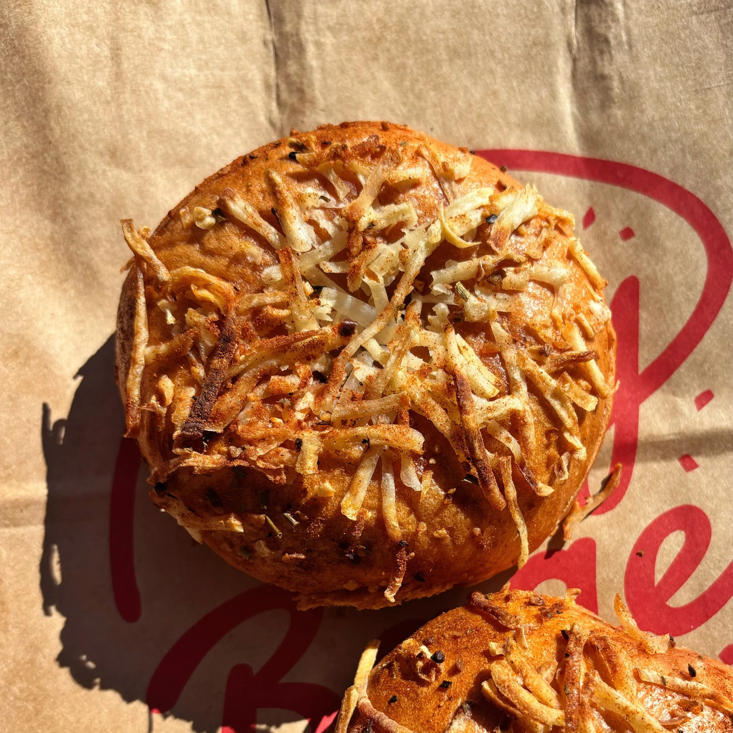 Patatas Bravas Bagel of the Week has been a hit so far! Chili tomato dough, shredded potatoes, and garlic &amp; paprika seasoning! Have you tried it yet? 
Available through Sunday!