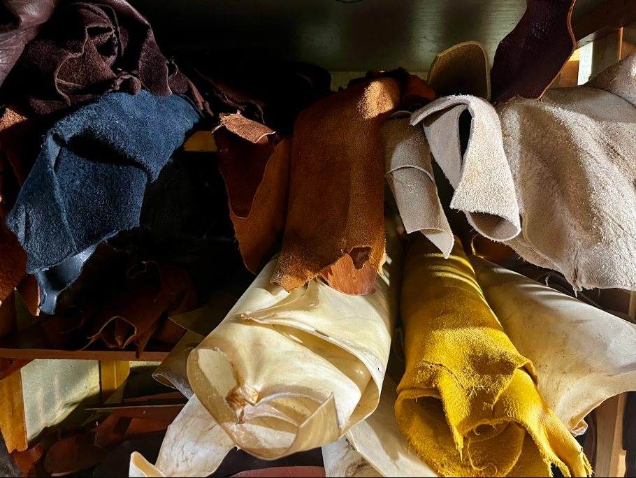 Rolled and draped leather and fabric materials stored on a shelf.