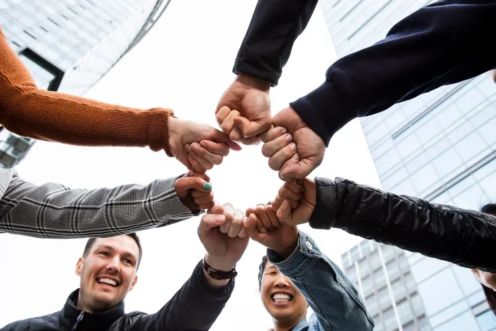 lawrence-anderson-portrait-team-hands-together.webp