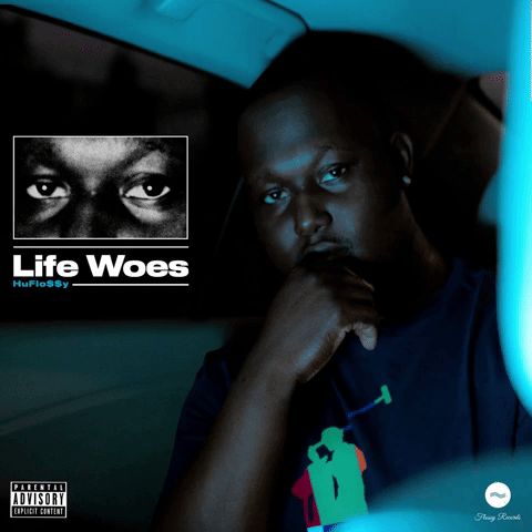 A dark-skinned man sitting inside a vehicle, looking thoughtfully at the camera, with a logo featuring another person's eyes and the text 'Life Woes' in the upper left corner.
