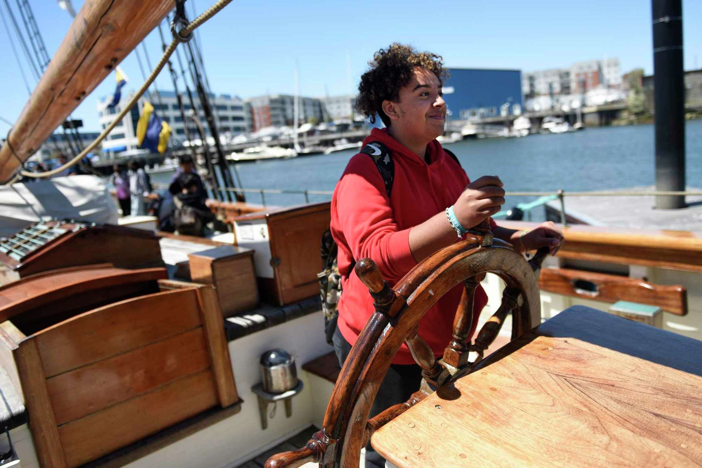  Eighth-grader Jefferson Hernandez takes the helm aboard a reproduction of the Amistad slave ship docked at Harbor Point in Stamford, Conn. Monday, May 9, 2022. Eighth grade students toured the ship to kick off the new partnership between Stamford Pu