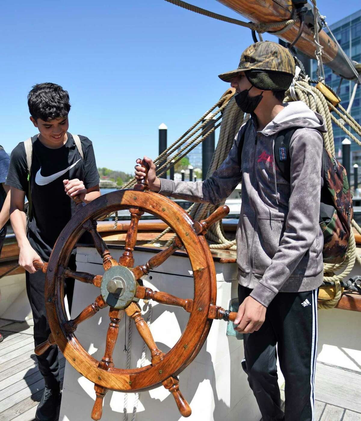  Eighth-graders Alejandro Guzman, left, and Arjun Manaise take the helm aboard a reproduction of the Amistad slave ship docked at Harbor Point in Stamford, Conn. Monday, May 9, 2022. Eighth grade students toured the ship to kick off the new partnersh