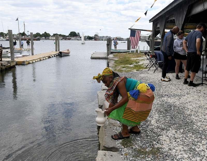  EvaE Peart, of New York, collects water from the river before a Juneteenth Celebration at the Mystic Seaport Museum on Sunday, June 19, 2022. The water was used later as a 'pouring libation' to honor ancestors in a traditional dance. The museum part