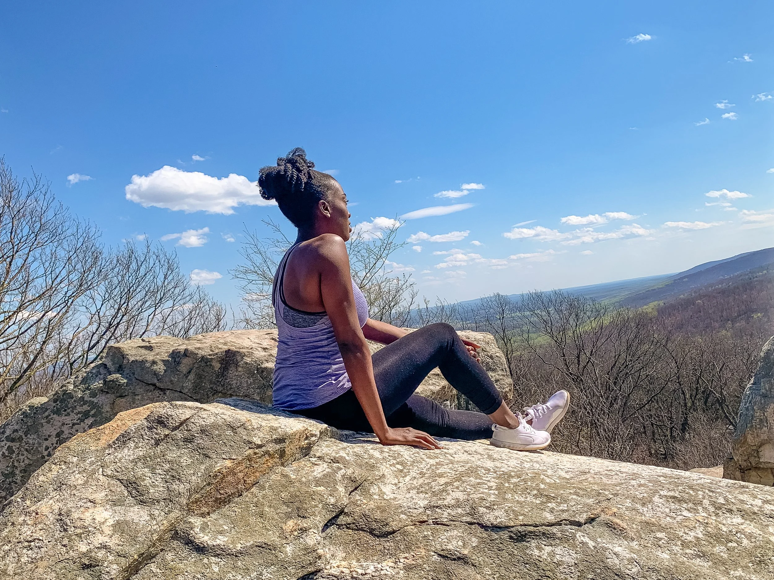 black woman sitting on rock looking away