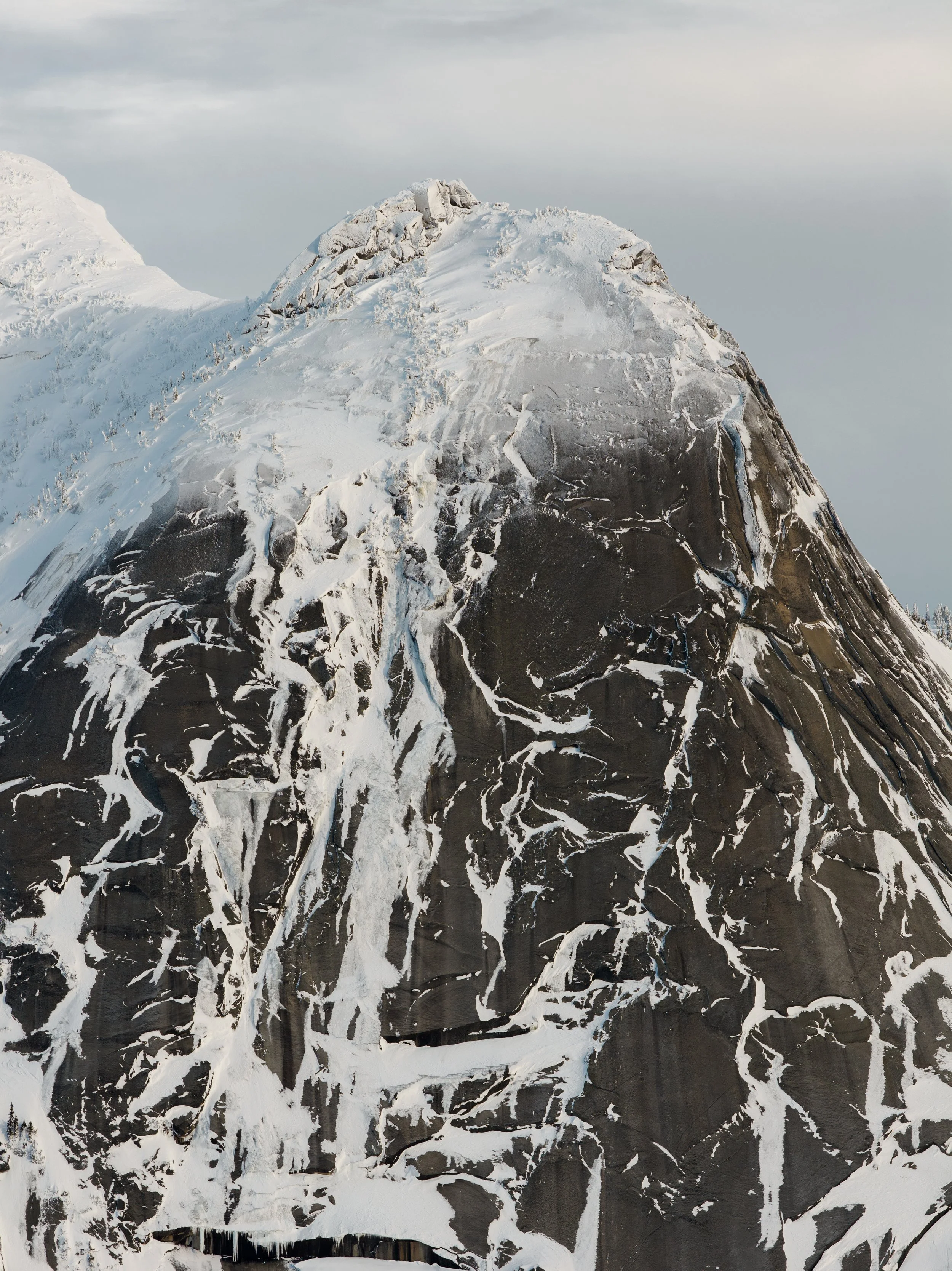 Snow-covered mountain with exposed rock and icy streaks.