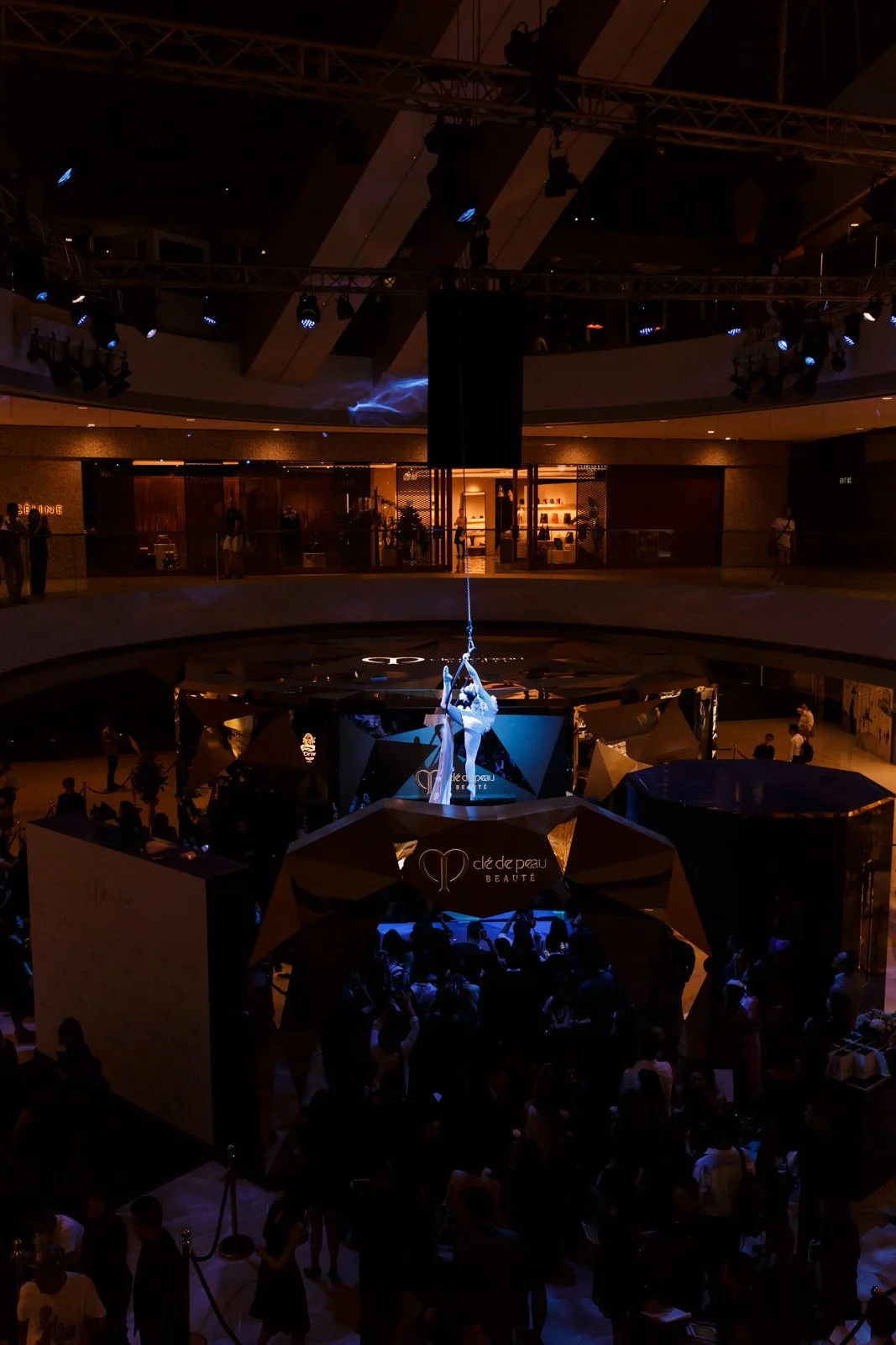 A dramatic aerial silk performance by BPM Productions Hong Kong suspended above the Clé de Peau Beauté exhibition floor in a high-end luxury mall.