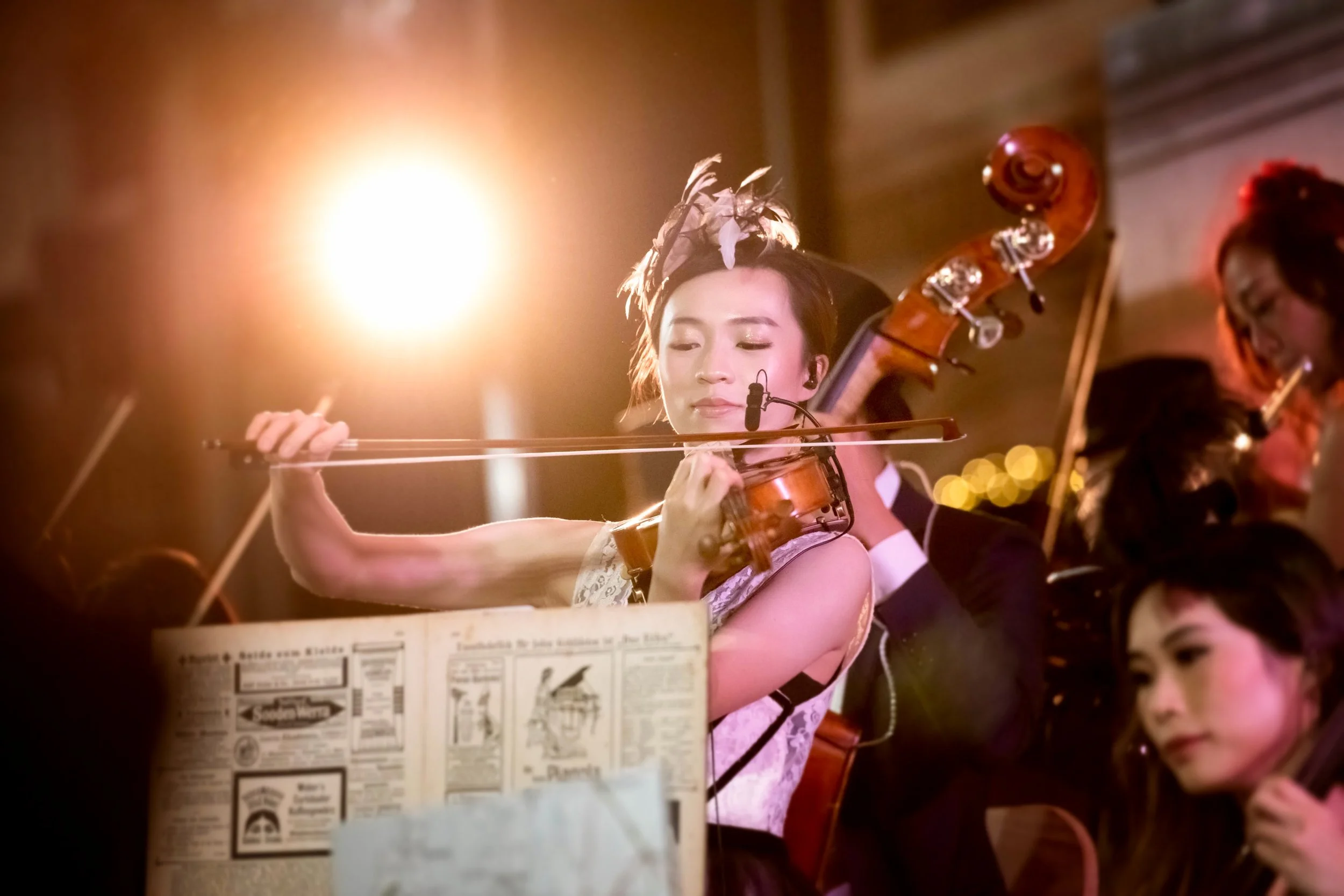 Live musical performance at The Peninsula Hong Kong's Christmas celebration, showing musicians playing violin and cello in the hotel lobby