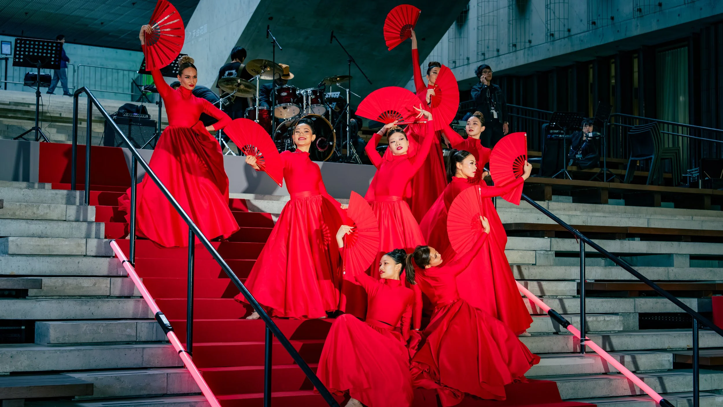 Performers from BPM Productions Hong Kong in vibrant red dresses performing a synchronized fan dance for the 2026 LIV Golf opening ceremony at the M+ Museum.