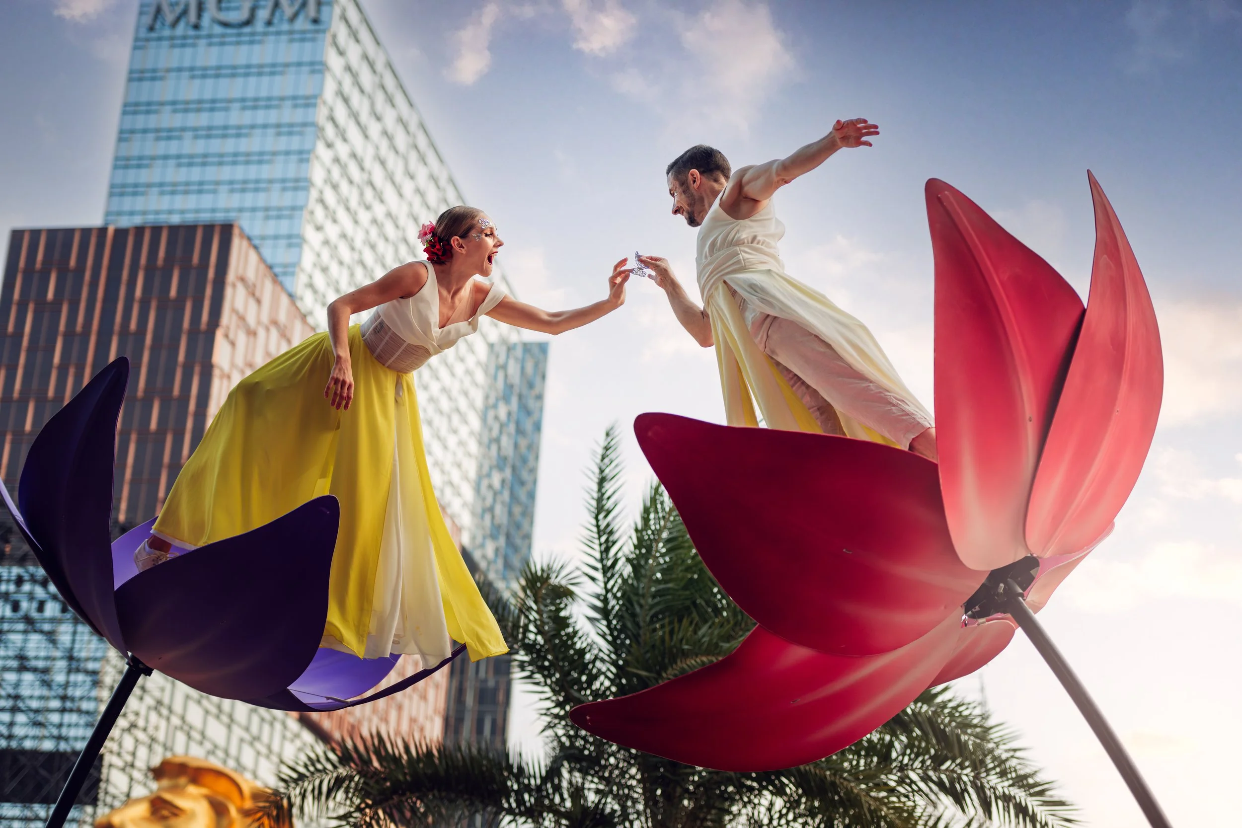 Two acrobatic performers from BPM Productions Hong Kong perform on high-altitude sway poles above giant blooming flower props at City of Dreams Macau during a 2024-2025 outdoor activation.