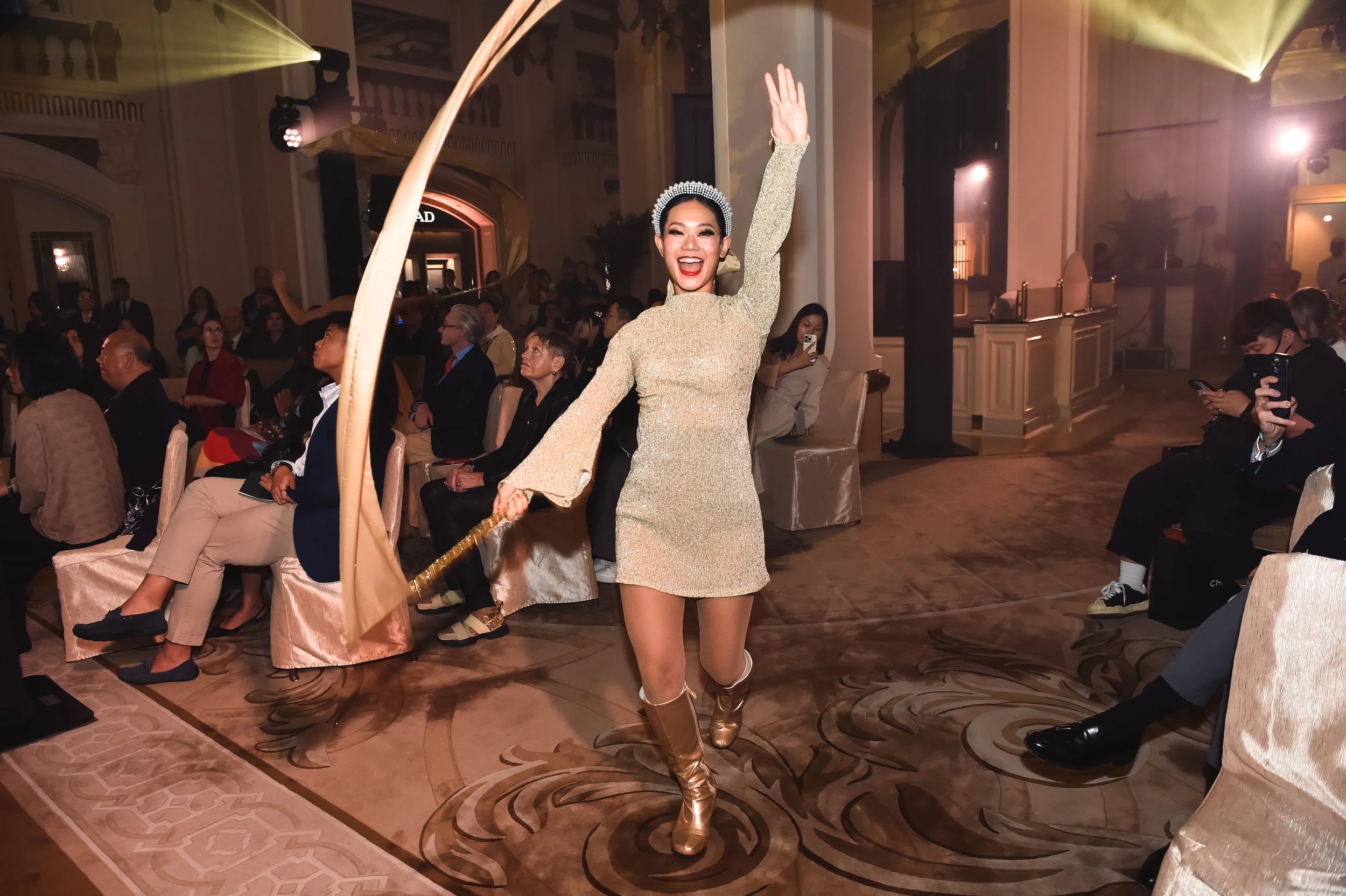 A female performer in a shimmering gold dress dances during the "The Peninsula Express" festive musical extravaganza in the lobby of The Peninsula Hong Kong.
