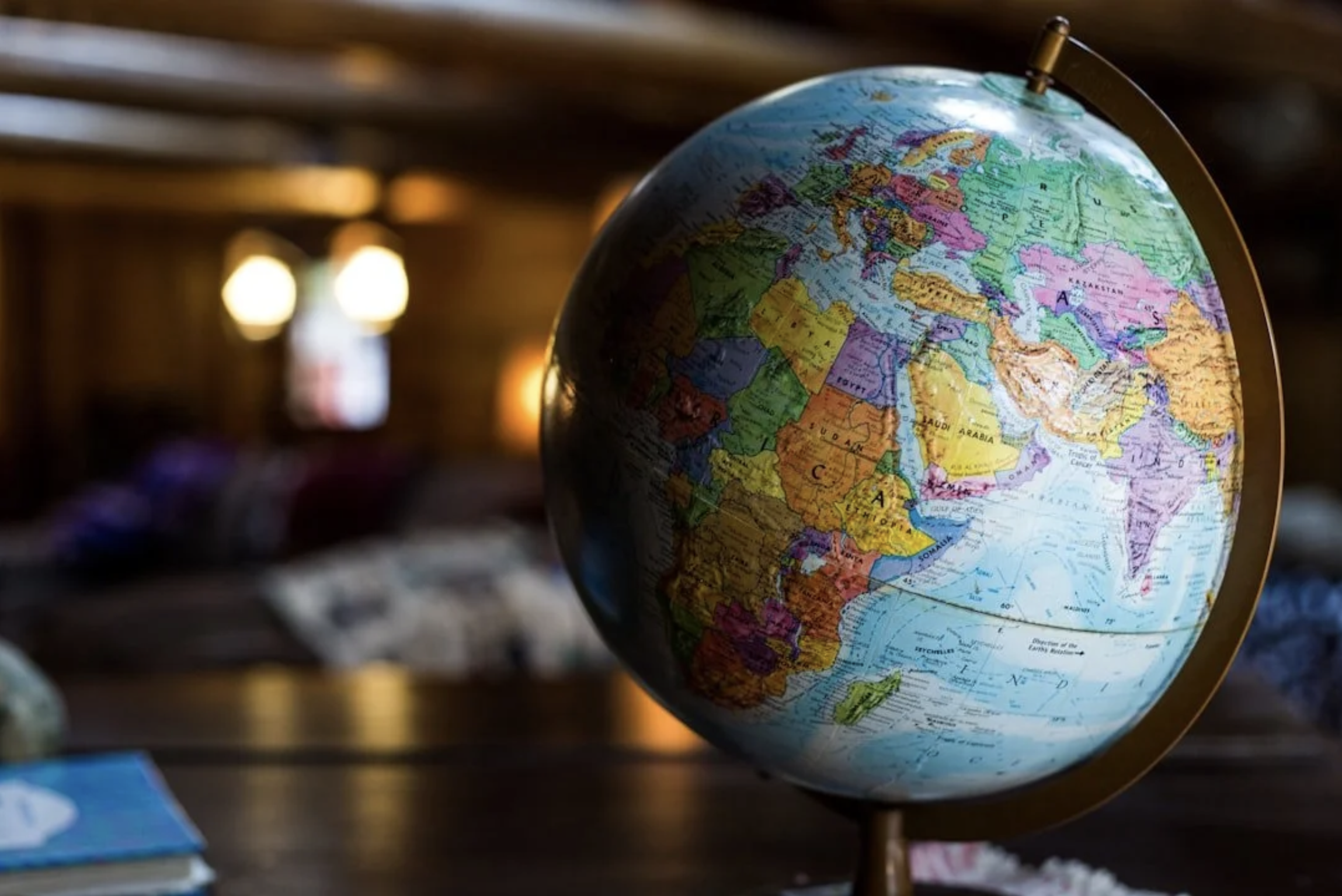 A globe showing continents including Europe, Africa, and parts of Asia, situated on a surface with blurred background lighting.