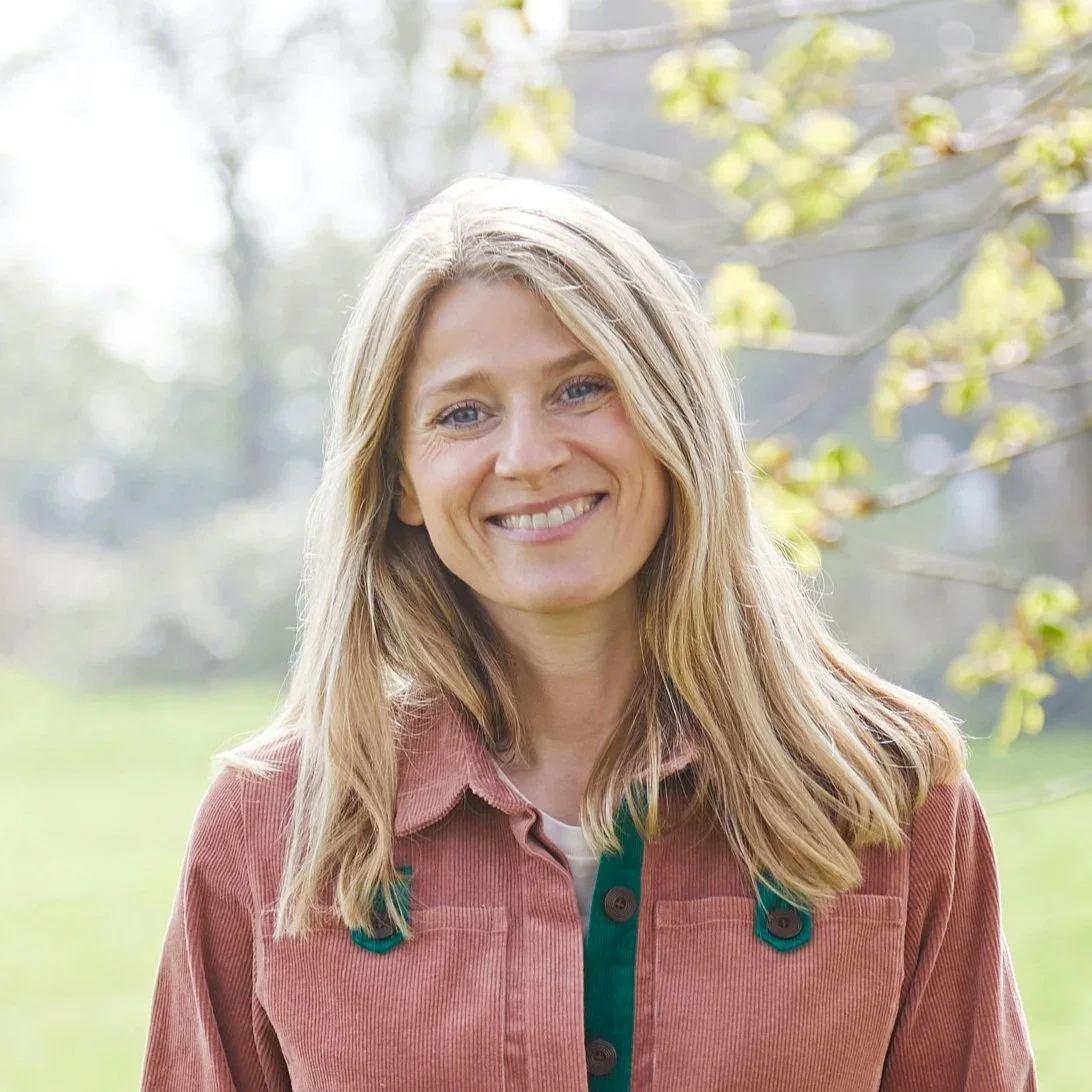 Photo of Lorna, smiling and standing in a field in Chichester surrounded by nature