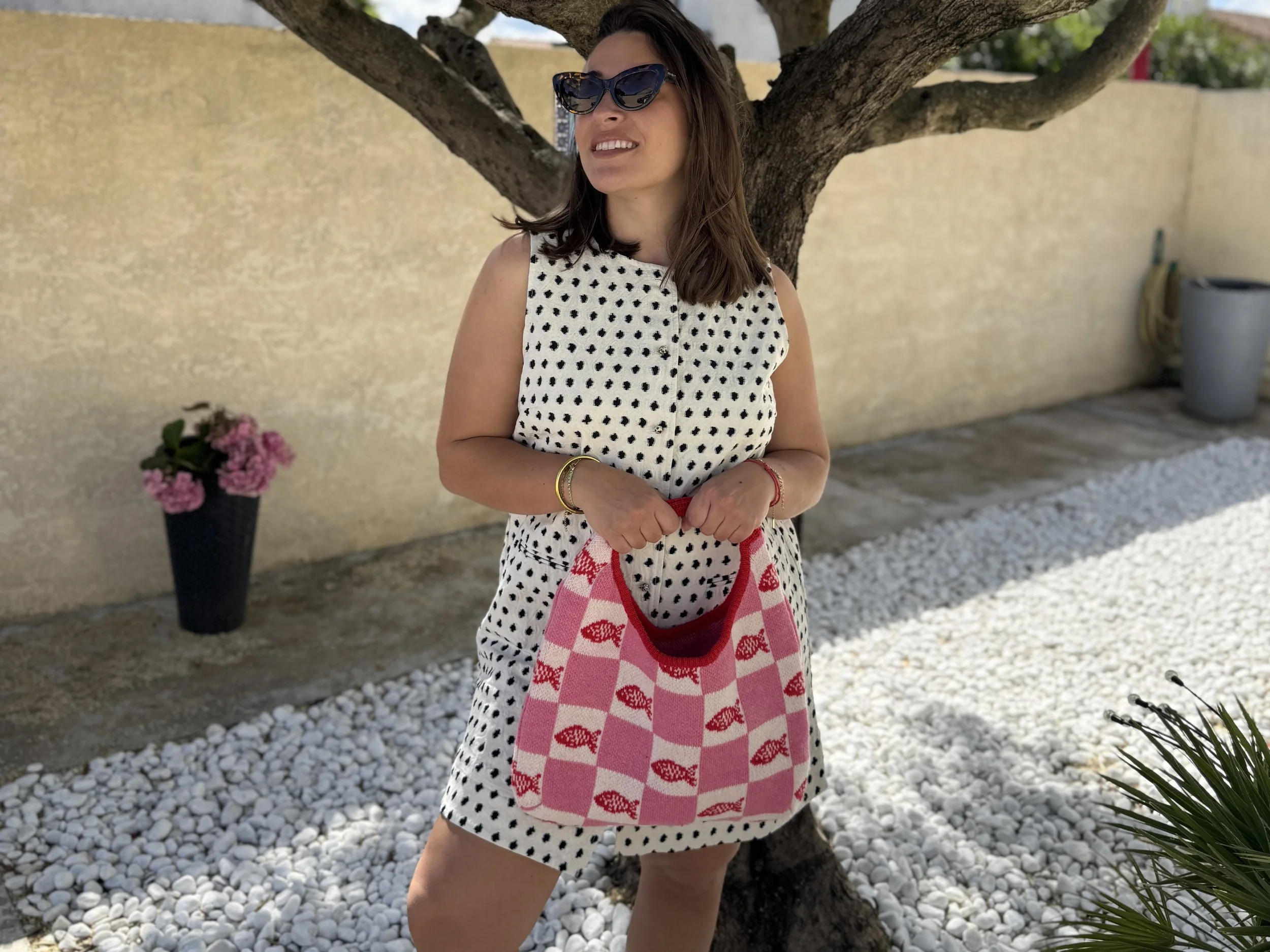 Une femme avec une robe à pois et un sac rose dammier