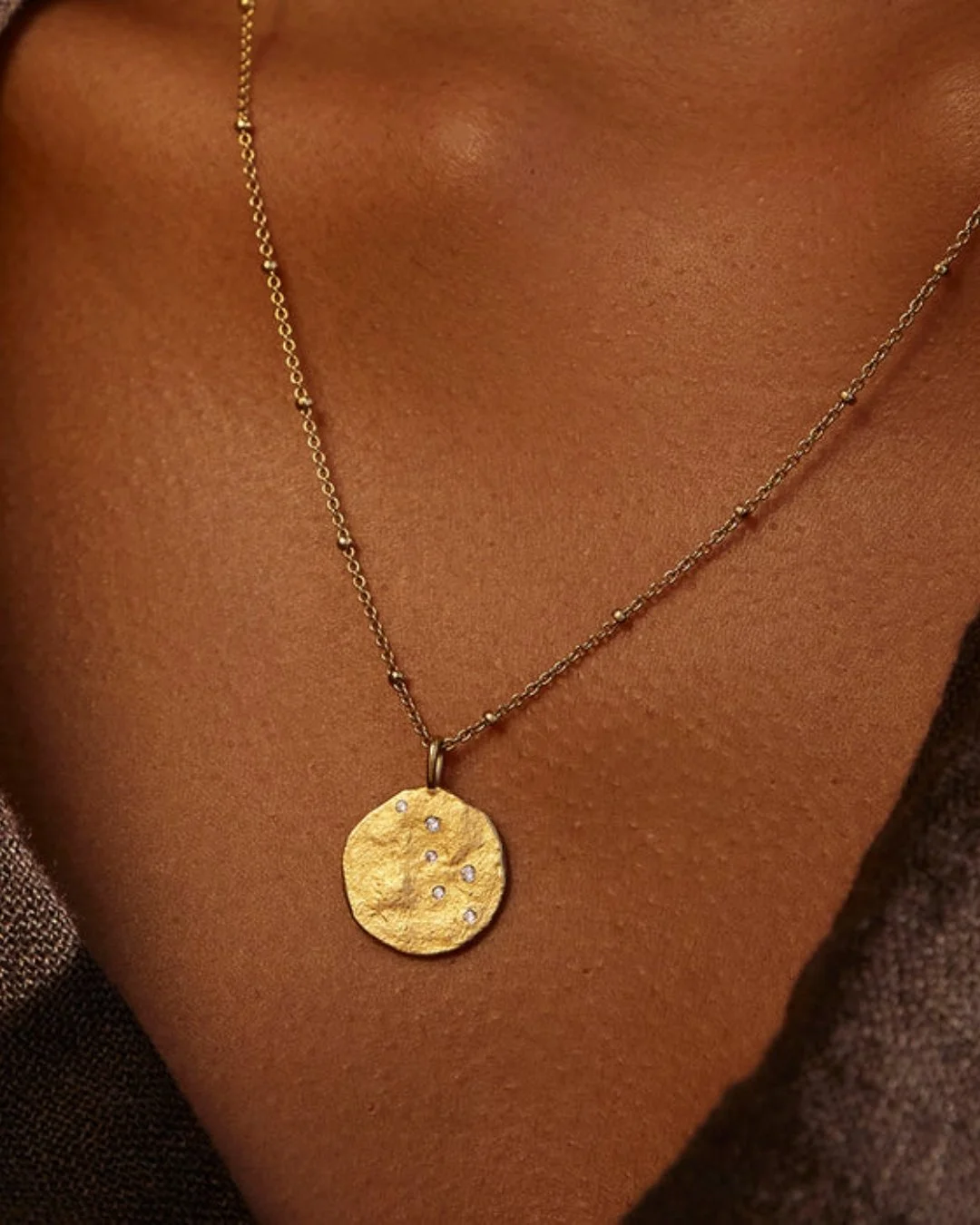 La poitrine d'une jeune femme qui porte un bijoux doré