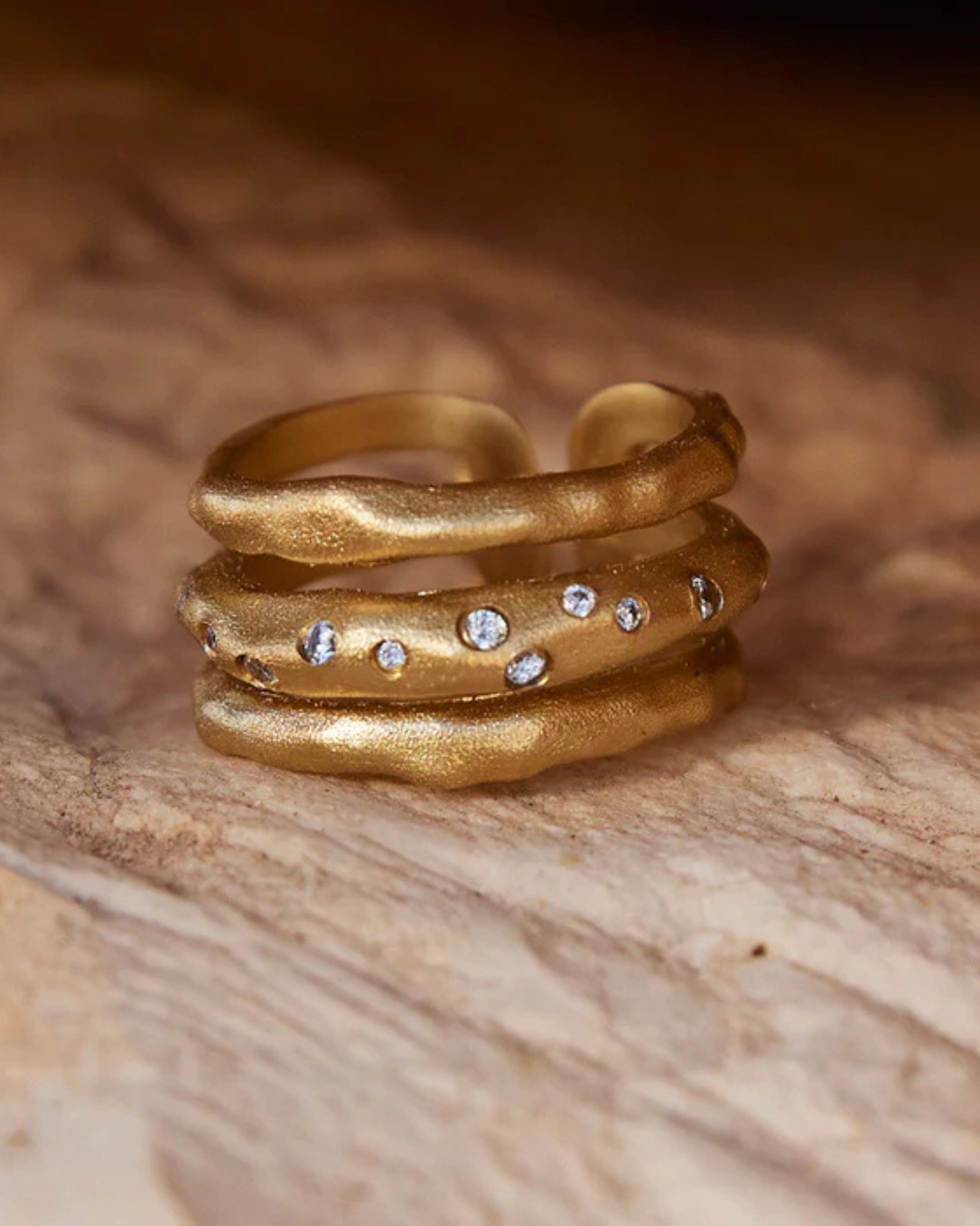 Bague Iris de la marque agapée trois rand avec pierre zircon posé sur un drap en lin