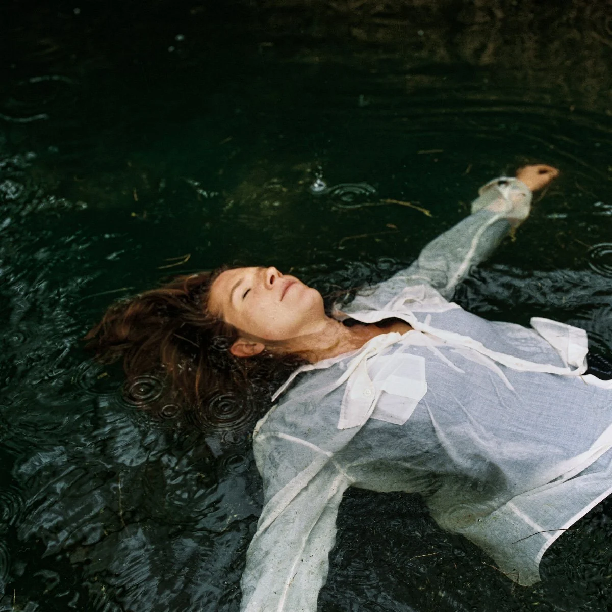Image issue d'un sujet de revue EPIC 19 : une femme flotte sur une eau sombre sous la pluie.