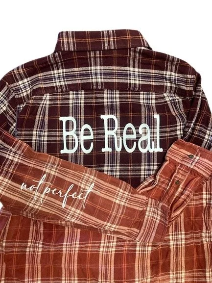 Flannel shirt with Be Real on the back and Not Perfect on sleeve
