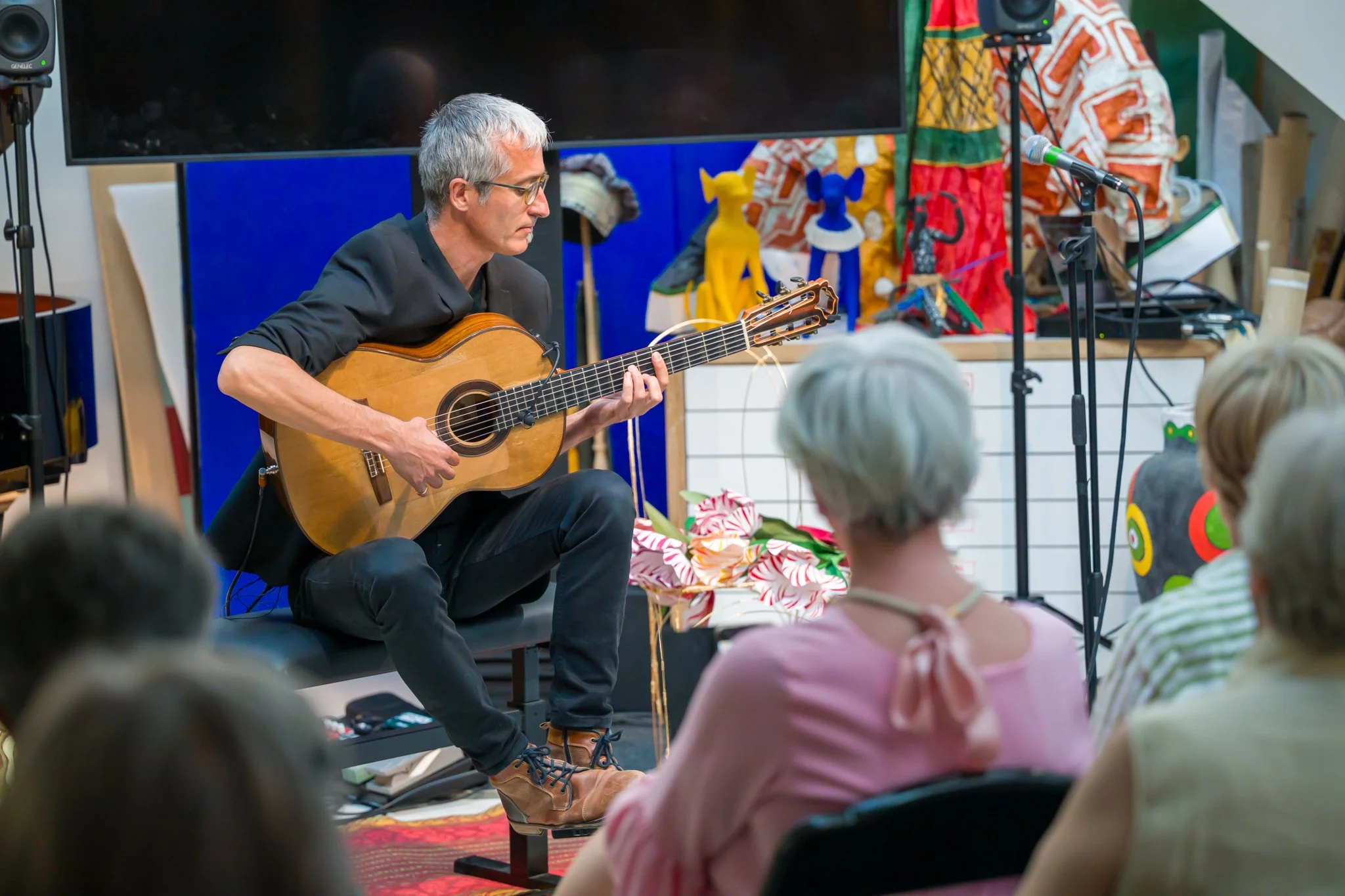 Un homme joue de la guitare acoustique lors d'une performance devant un public.