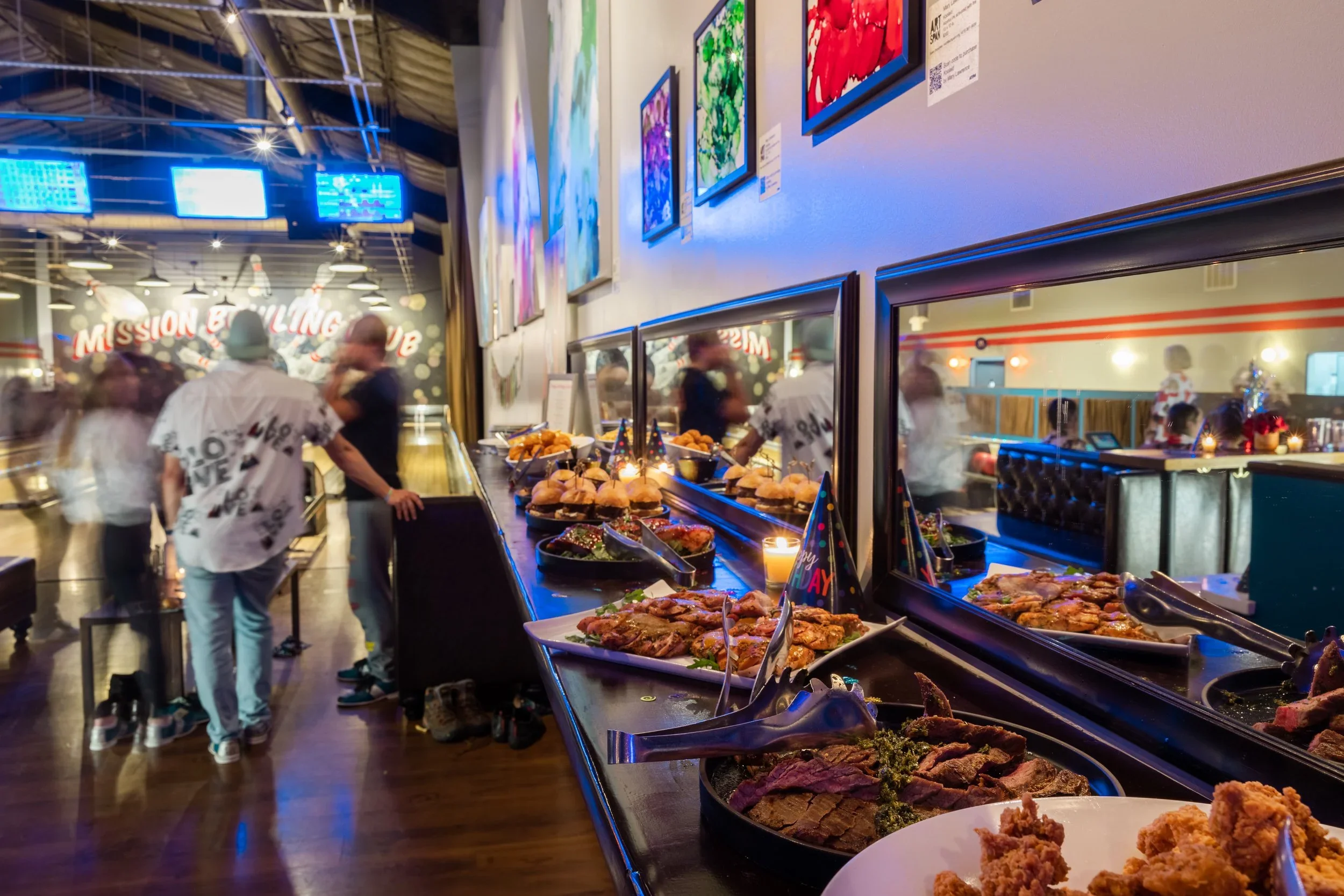 Assorted bowls of fried and spicy food items on a black table, including fried chicken, cheese balls, and fries in a casual dining setting.