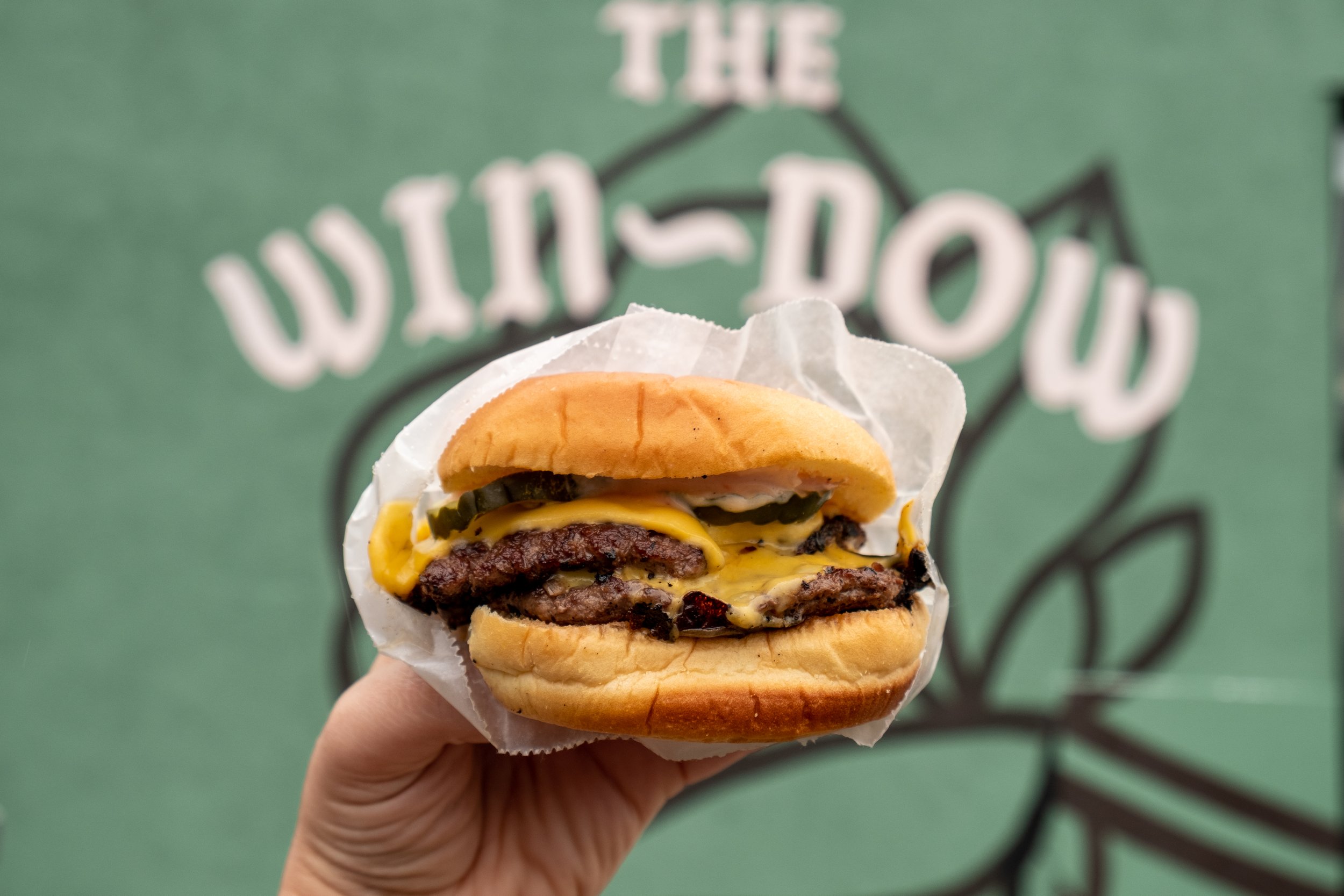  double cheeseburger in front of the Win~Dow logo 