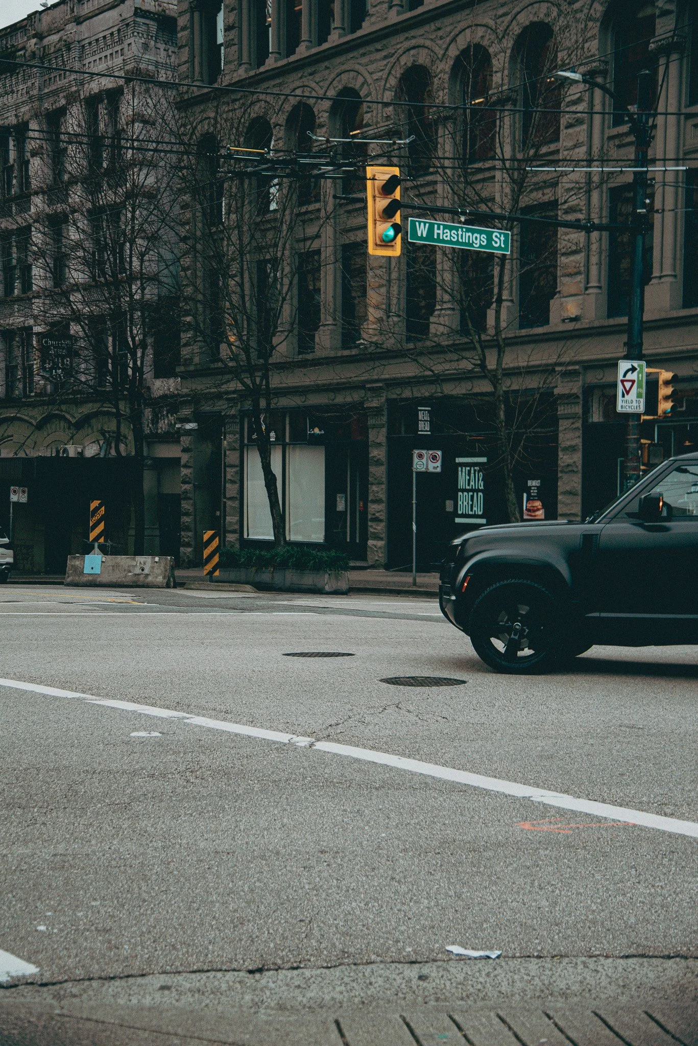 A black Land Rover defender crosses through Hastings street in Vancouver, BC