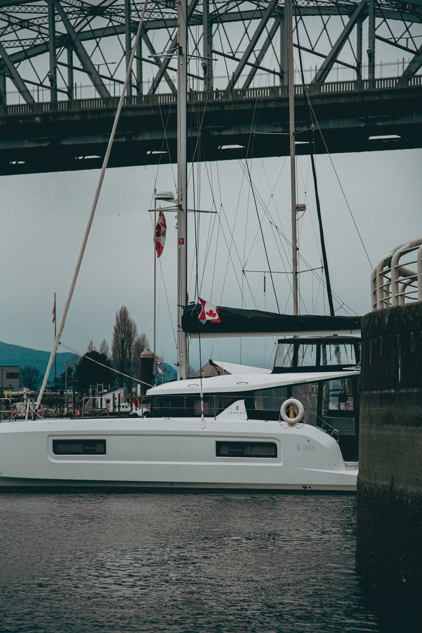 Dark image of a small yacht in the Vancouver bc harbour with a Canadian flag being hoisted.