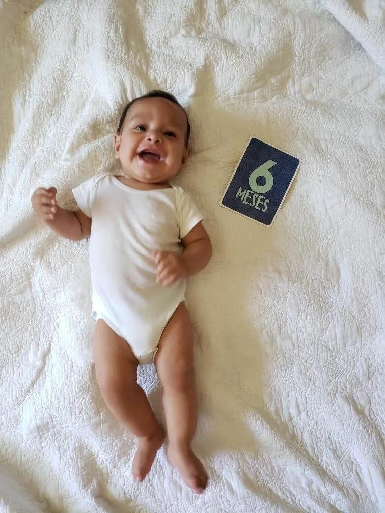 Smiling baby with "6 meses" sign Pittsburgh birth doula