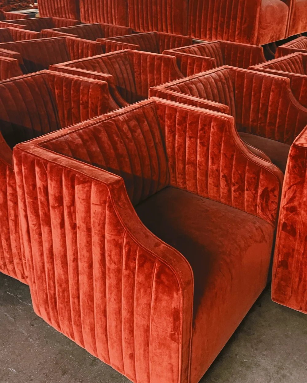A production run of channel-back lounge chairs in rust velvet on the floor of the Trend Contract Furnishings factory in Carson, California
