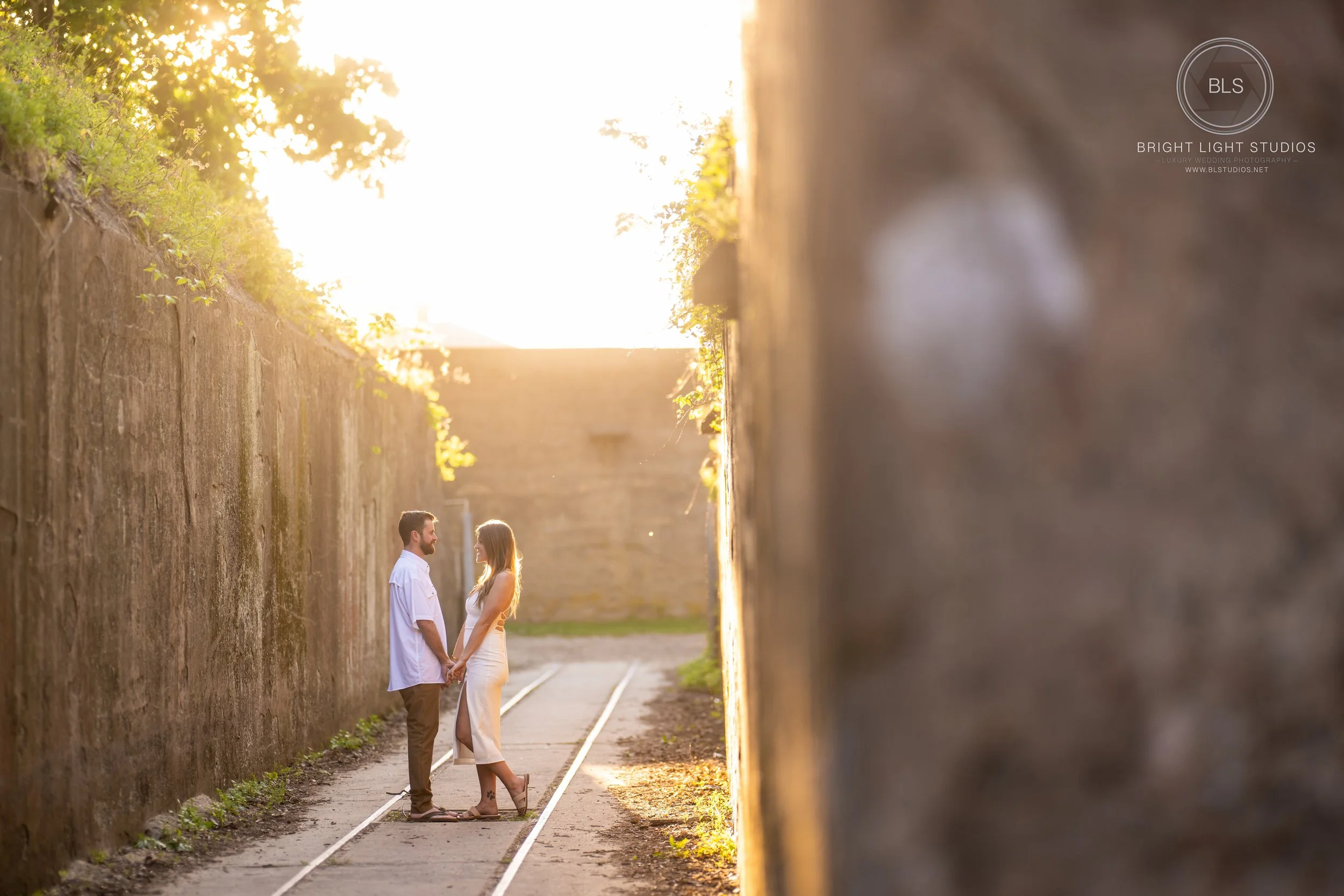 Holly and parker pose at a rail road at sandy hook beach for their engagement photoshoot