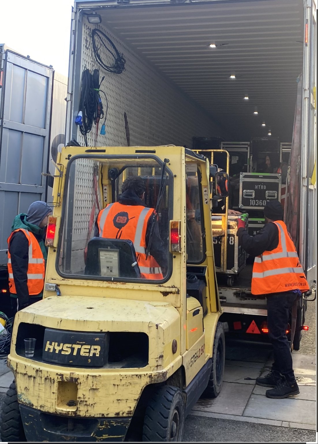 Bambo crew in orange safety vests loading equipment into a truck with a forklift.